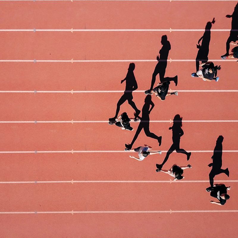 Menschen laufen auf einer Tartanbahn – Sinnbild für Dynamik, Fokus und gemeinsames Lernen in Bewegung.